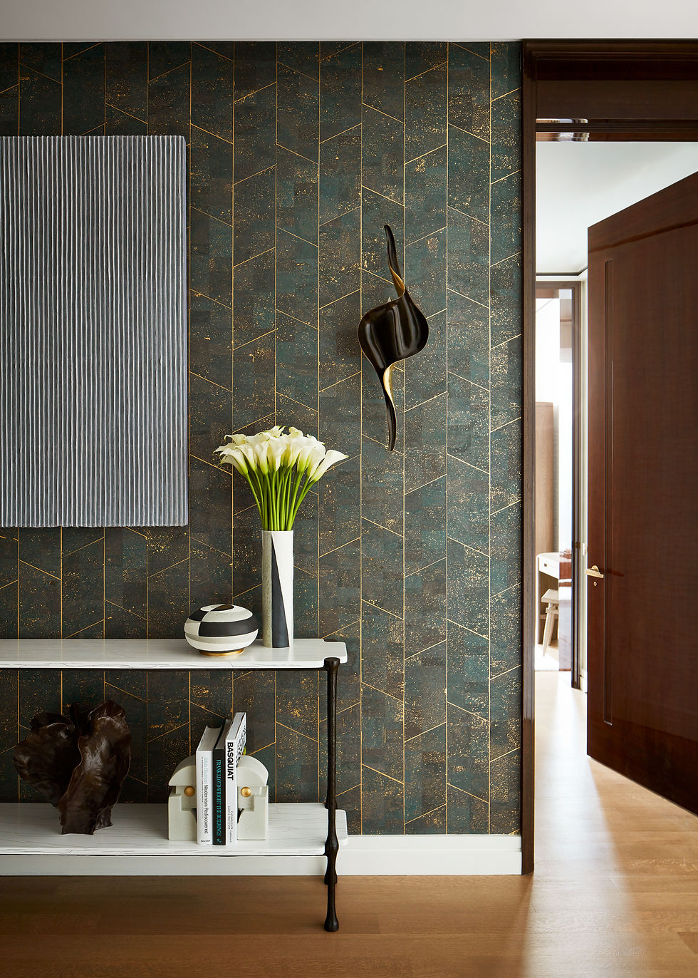 Gallery detail at the 53W53 residence, showing a patterned wall, console, flowers and abstract sculptural objects.