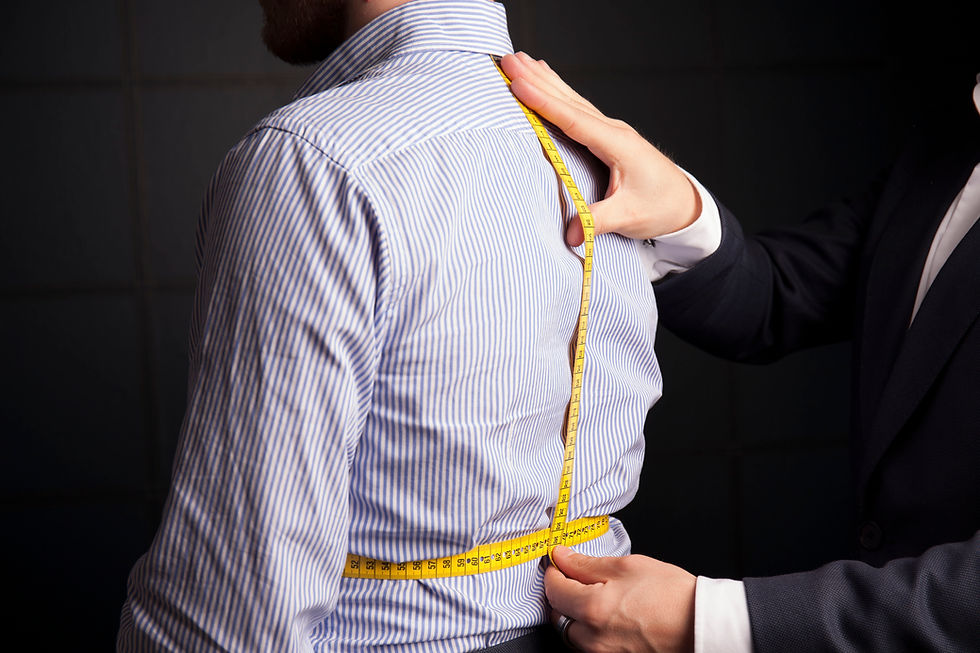 A tailor takes body measurements with a flexible tape.