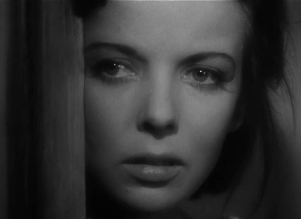 Close-up of a woman's face looking through a doorway, in black and white. Her expression appears tense and focused. Ida Lupino stars in the classic Warner Brothers psychological adventure movie 1941 Hollywood film "The Sea Wolf"