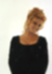 Smiling woman with curly red hair in a sequined black dress and dangling earrings, set against a plain white background. Color portrait of young singing dancing Hollywood movie star Vegas entertainer TV film actress sex symbol kitten legend icon Ann-Margret