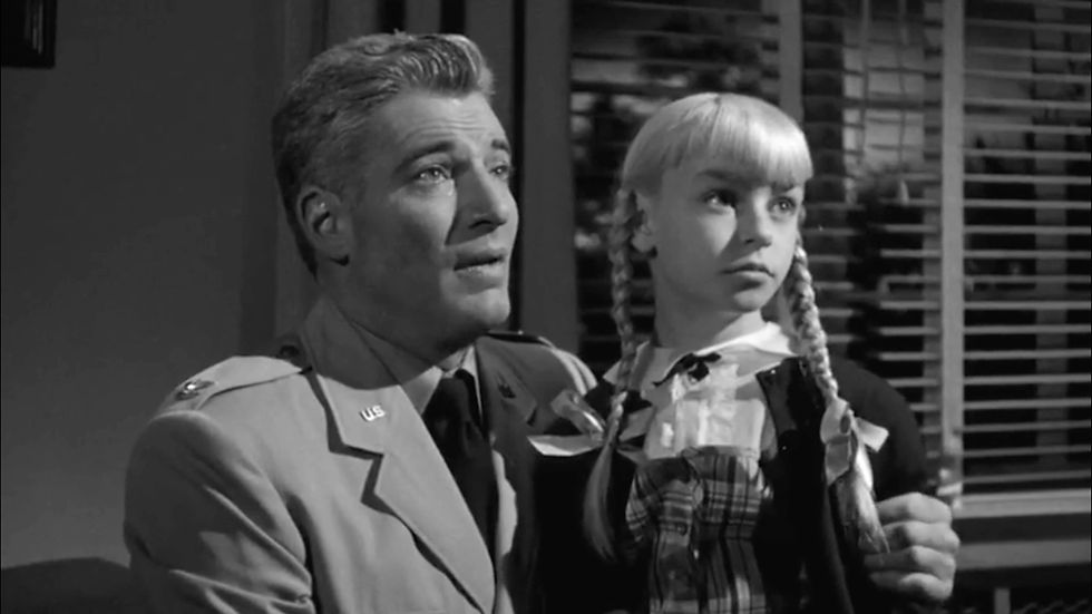 Man in uniform and girl with braids look intently off-screen in a dimly lit room with blinds. Both appear concerned. Black and white image. William Hopper and Patty McCormack are father and daughter in the cult classic film melodrama horror thriller Hollywood movie "The Bad Seed"