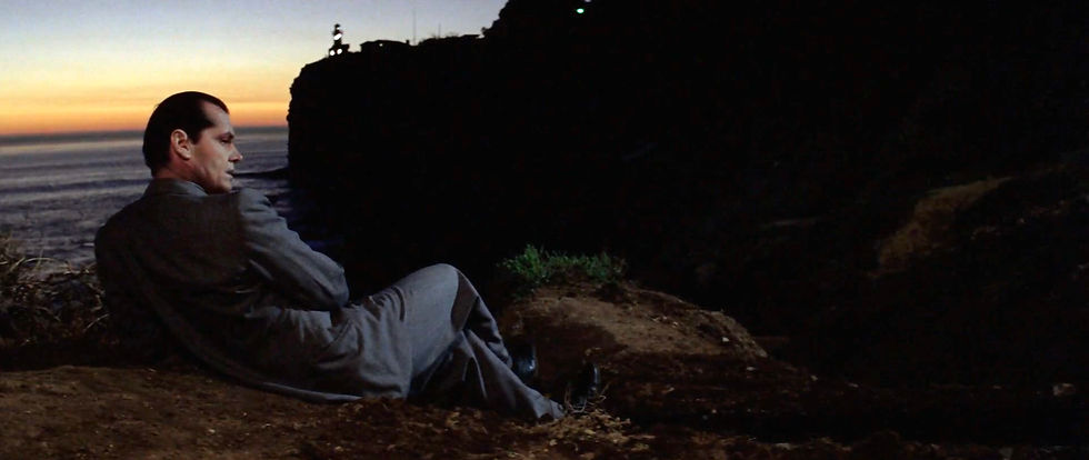 Man in a suit sits pensively on a cliff at sunset, overlooking the ocean. Silhouette of another person is visible at the cliff's edge. Jack Nicholson in Los Angeles sunset in the classic 1970s Hollywood movie neo-film noir detective thriller story "Chinatown"