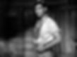 Man in a rolled-up shirt stands in a rustic cabin, appearing contemplative. Wooden walls form the background. Black-and-white image. Clark Gabel without a mustache young in the classic Hollywood film MGM Pre-Code movie "Red Dust"