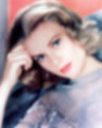 Blonde woman with short waves rests her head on hand, wearing a sheer floral blouse, red lipstick, and an earring. Soft, contemplative mood. Color glamour portrait photo of Hollywood movie star film actress young Grace Kelly Princess Grace of Monaco