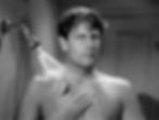 Man in a shower, water spraying from showerhead. Tiled walls, serious expression, wet hair. Black and white image. Joel McCrea hears a woman's voice in the shower in the classic Hollywood romantic comedy film rom-com movie 1940s "The More the Merrier".