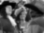 Three people in period costumes, wearing ornate hats, laughing in a lively setting. The mood is joyful with decorative attire. George Hassell, Mary Forbes, and Lionel Atwell in the classic 1930s swashbuckling pirate film classic Hollywood adventure movie "Captain Blood"