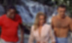 Three tense people—man in red shirt, blonde woman, shirtless man—stand before a waterfall in a jungle. John Kitzmiller, Ursula Andress, and Sean Connery in the first classic James Bond movie espionage spy thriller 007 film 1962 "Dr. No"