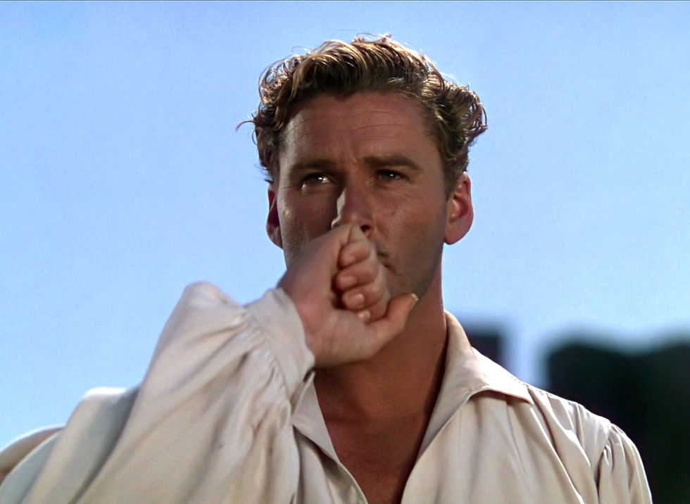 Close-up of a serious man in a white shirt against a blue sky, his face partly covered by a clenched hand in the foreground. Errol Flynn kisses the ring in the classic Hollywood costume drama 1939 movie about Queen Elizabeth I and the Earl of Essex in "The Private Lives of Elizabeth and Essex"