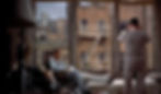 Man in a wheelchair with leg cast sits inside, facing window. Another man stands with binoculars, looking out at brick buildings. Atmosphere is tense. James Jimmy Stewart with a broken leg and Wendell Corey looking at the neighbors in the Alfred Hitchcock classic Hollywood film suspense movie "Rear Window"