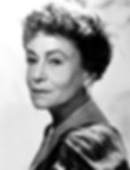 Elderly woman with short curly hair in a patterned dress, wearing a necklace and earrings, looks serenely at the camera. Black and white photo. Portrait photo of Hollywood movie star character film actress Thelma Ritter