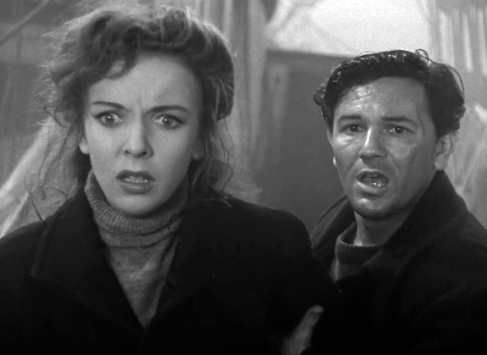 A woman and a man look surprised and concerned in a black-and-white scene. Their expressions indicate urgency. Background is blurred. Ida Lupino and John Garfield in the classic Warner Brothers psychological adventure movie 1941 Hollywood film "The Sea Wolf"