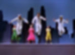 Sailors in white uniforms jump energetically with three women in colorful dresses on a stage. City skyline backdrop sets a lively mood. Dance Frank Sinatra, Vera-Ellen, Carol Hanney in the classic movie Hollywood MGM musical film On The Town