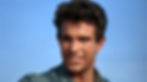 Man with short hair and a slight smile, wearing a denim shirt, against a clear blue sky background. Appears relaxed and confident. Warren Beatty stars in the classic 1960s Hollywood film romance movie about sex and repression, "Splendor in the Grass"