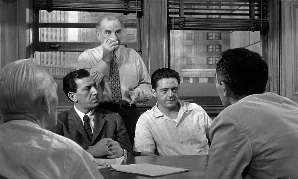 Four men are engaged in a serious discussion around a table in a room with large windows. One man stands, holding a handkerchief. Black and white. Jack Klugman, Ed Begley, and Edward Binns in the classic movie Hollywood courtroom drama film "12 Angry Men" twelve