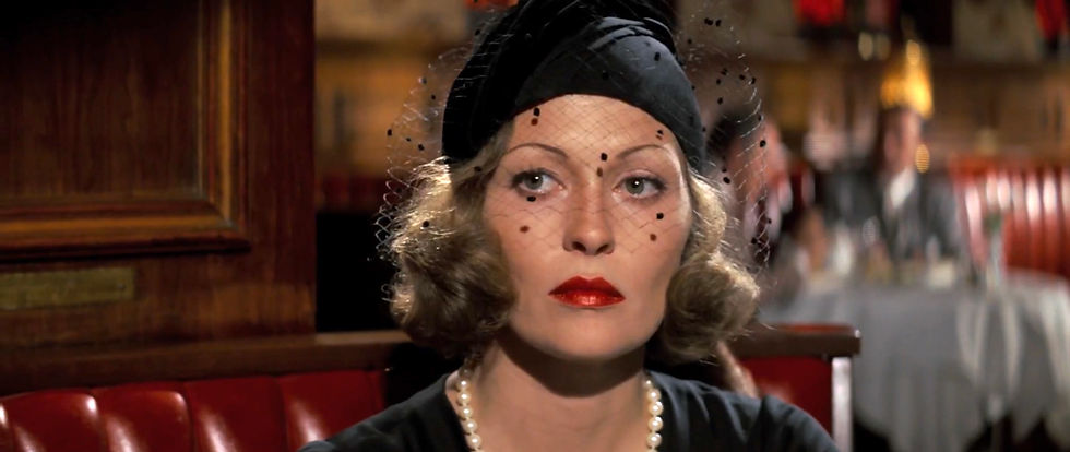 Woman with veil and red lipstick sits in a wooden booth, wearing pearls and black hat, in a dimly lit restaurant. Mood is mysterious. Faye Dunaway stars in the classic 1970s Hollywood movie neo-film noir detective thriller story "Chinatown"