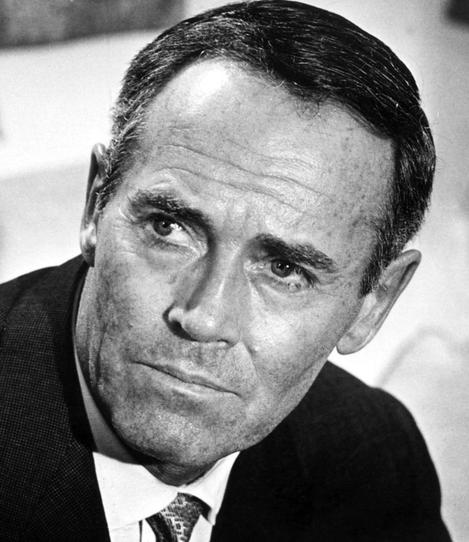 Black and white portrait of a man with a thoughtful expression, wearing a suit and tie. The background is blurred and neutral. Portrait photo of Hollywood movie star, film actor hero Henry "Hank" Fonda, middle aged
