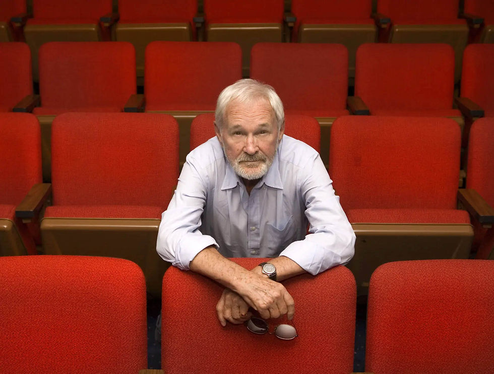 color photo of film and television director Norman Jewison sitting in red chair movie theater seats