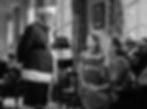 Santa stands in a room talking to a young girl and woman. The setting is cozy with large windows and plants. The girl's expression is curious. Edmund Gwenn, Natalie Wood, and Maureen O'Hara star in the classic movie Hollywood holiday Christmas Santa Claus film "Miracle on 34th Street"