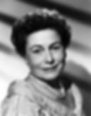 Smiling woman in lace dress and pearls, black and white portrait. Soft lighting, subtle shadows on background create an elegant mood. Hollywood movie star film character actress portrait photo of Thelma Ritter