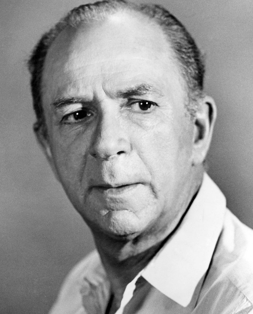 Elderly man in a white shirt, gazing seriously at the camera. Neutral gray background, close-up portrait with a pensive mood. Hollywood movie star film actor portrait photo of younger Jack Albertson