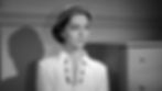 Woman in elegant white dress and hat stands against a plain background, with a contemplative expression. Shadow cast on the wall. Black and white image. Joan Weldon stars in the classic 1950s Golden Age horror movie science fiction sci-fi big bug giant ants film "Them!"