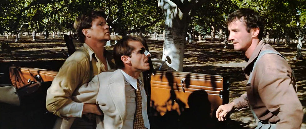 Three men stand tensely by a car in an orchard. One wears a cream suit with a bandage on his nose. Shadows cast by the trees enhance the mood. Jesse Vint, Jim Burk, Denny Arnold and Jack Nicholson fight in the classic 1970s Hollywood movie neo-film noir detective thriller story "Chinatown"