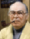 Elderly man with glasses wears a yellow sweater, smoking a pipe. Wood-paneled background, calm expression, warm indoor setting. color portrait photo of Hollywood screenwriter writer John Michael Hayes older