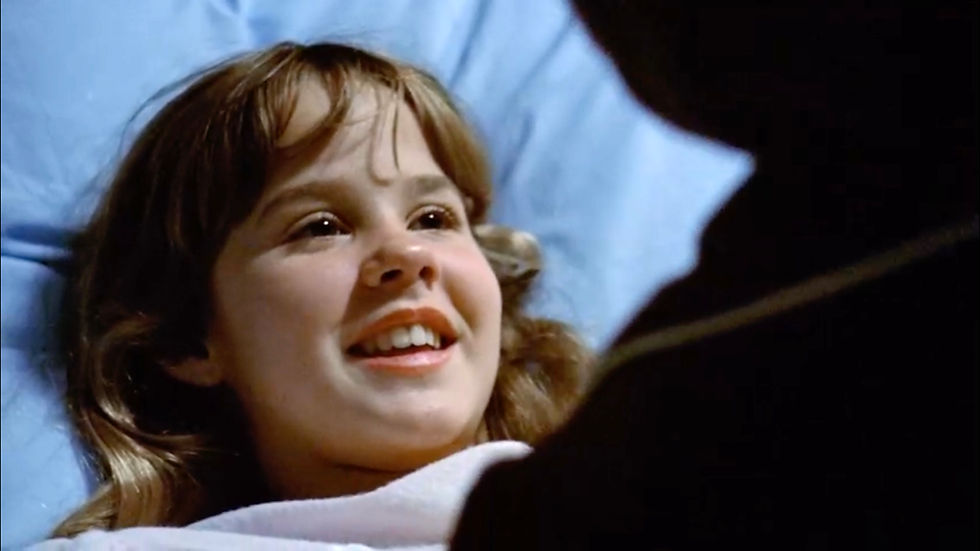 Smiling young girl лежing in bed with a blue pillow, looking up at someone in the foreground, warm and happy mood. Linda Blair chats with her mom Ellen Burstyn in the scariest movie of all time, classic horror film about the devil and possession, 1973 "The Exorcist".