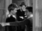 A woman in a floral dress faces a man and a boy in a suit. The boy points to the left. The setting is a doorway; emotions are tense. Black and white. Jean Arthur, Joel McCrea and Stanley Clements in the classic Hollywood romantic comedy film rom-com movie 1940s "The More the Merrier".