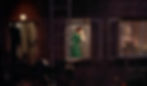 Woman in green dress by window touches her head. Dimly lit, brick wall exterior. Another person walks inside under a round light. Moody night scene. Judith Evelyn is Miss Lonelyhearts in the Alfred Hitchcock classic Hollywood film suspense movie "Rear Window"