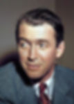 Man in a suit with a patterned tie gazes to the side. Neutral background, soft lighting, and a contemplative expression. Candid Color portrait photo of Hollywood movie star film actor middle aged older James Jimmy Stewart