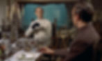Man in white with black glove sits at candlelit dinner table, facing another man in a formal room with glassware and fruit. John Wiseman and Sean Connery in the mad scientists lair in the first classic James Bond movie espionage spy thriller 007 film 1962 "Dr. No"