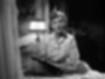 Woman in striped pajamas sits on a bed with a notebook and pen, lit by a lamp in a dimly lit room, appearing contemplative. Jean Arthur writes in her diary in the classic Hollywood romantic comedy film rom-com movie 1940s "The More the Merrier".