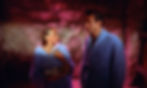 Woman and man in blue robes face each other in a pink-lit cave, looking tense and serious. Ursula Andress and Sean Connery in the first classic James Bond movie espionage spy thriller 007 film 1962 "Dr. No"