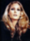 Portrait of a woman with long wavy blonde hair and dramatic makeup, gazing upward against a dark background. Color portrait of Swiss Hollywood movie star film actress international sex symbol young Ursula Andress.