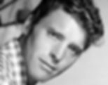 Black and white portrait of a man with wavy hair in a checkered shirt, looking intently at the camera. Soft lighting and blurred background. Portrait photo of younger Hollywood movie star film actor producer icon tough guy Burt Lancaster