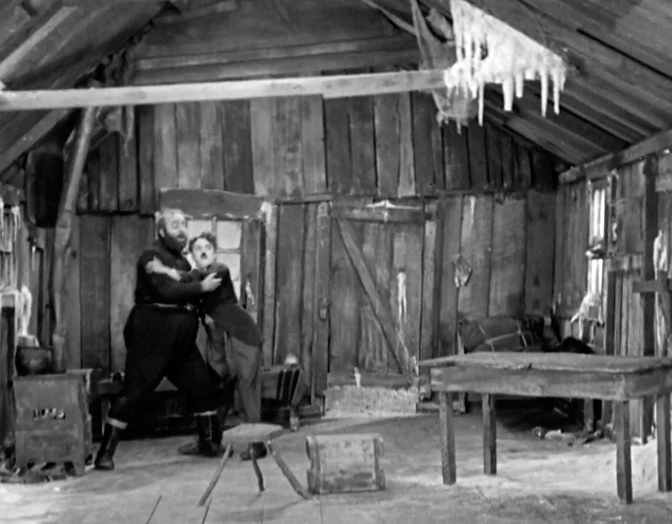 Mack Swain and The Tramp lone prospector feel their cabin tilt in Charles Charlie Chaplin's Hollywood classic silent film movie masterpiece in Alaska "The Gold Rush"