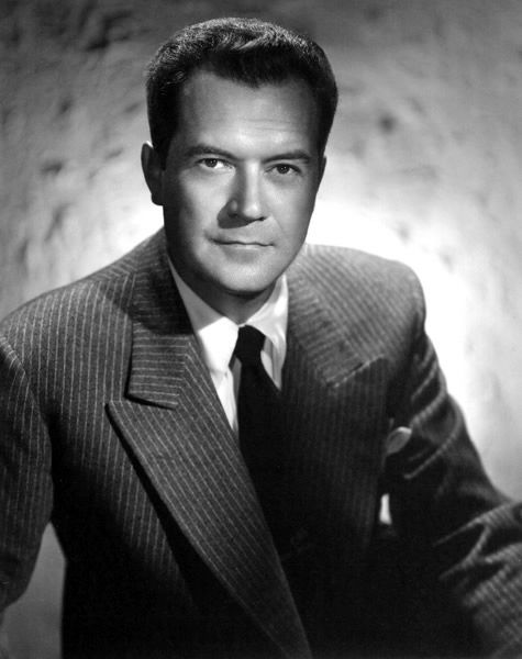 Man in a pinstripe suit and tie poses confidently against a textured background. Black and white, serious expression, classic style. Portrait photo of radio and movie star film actor character detective Frank Lovejoy young