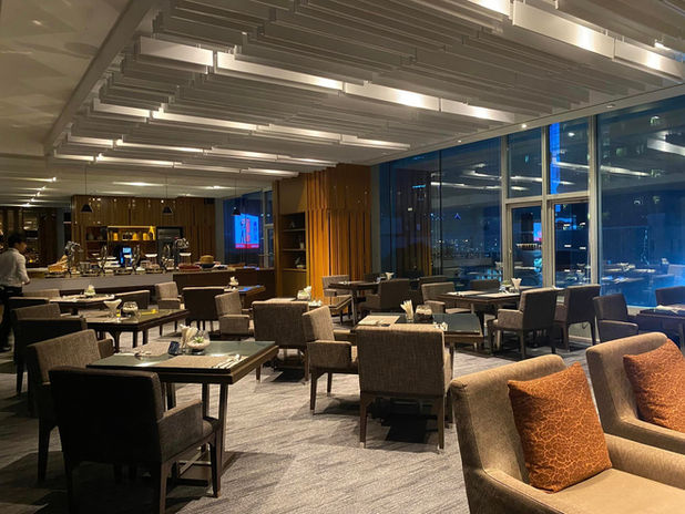 Modern reception desk with wood slat design, brochures on display, and grey lounge chairs in background.