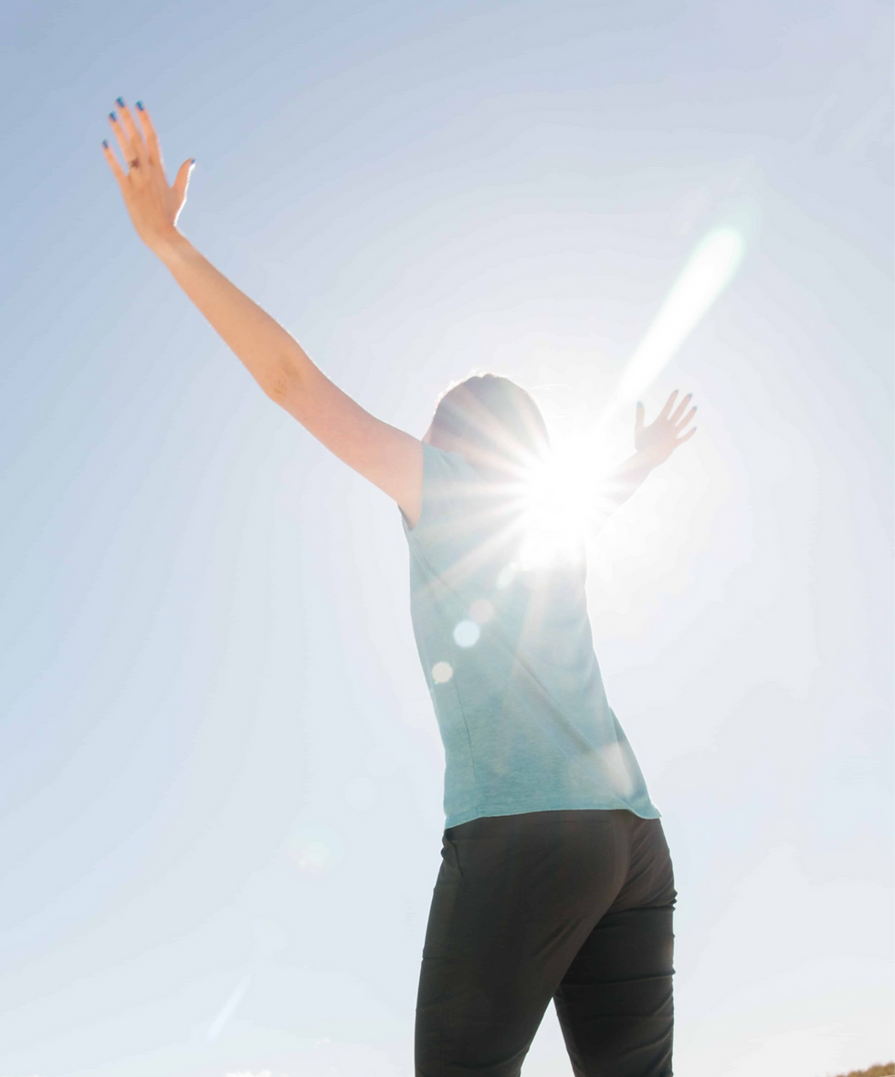 Woman lifting hands towards sun