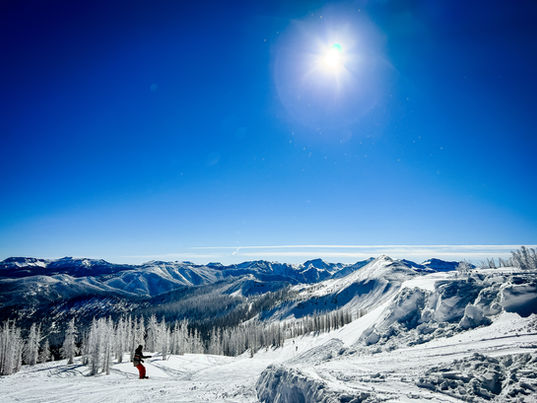 A skier on Wolf Creek Pass glides down the snowy mountain under a bluebird sky. 