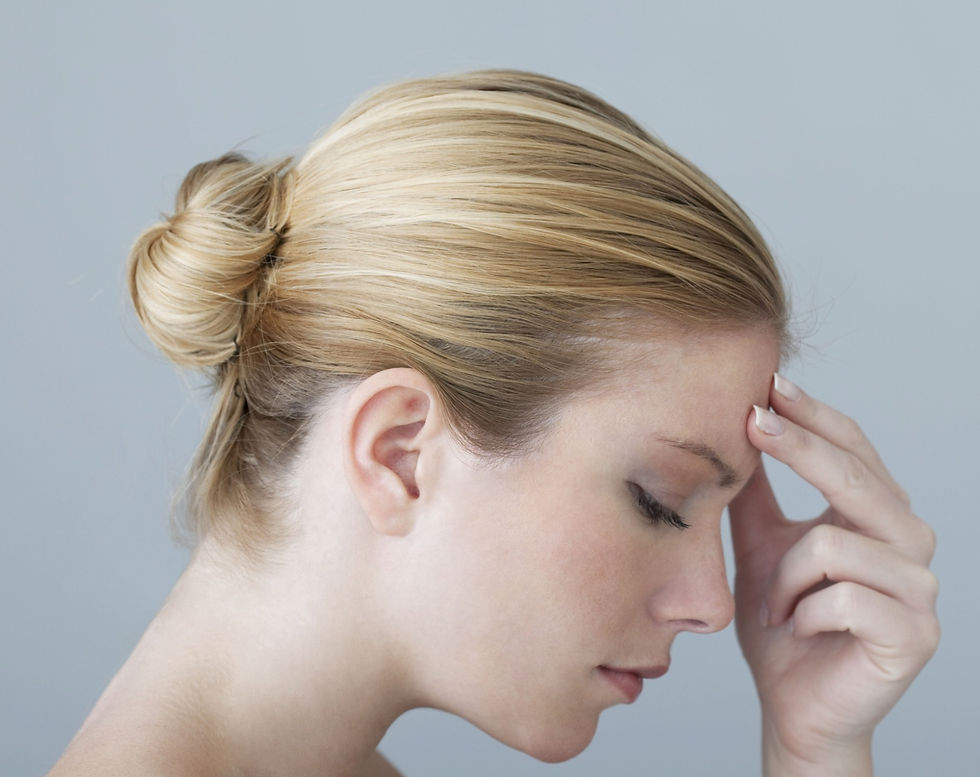 A lady with a headache, with can be treated with massage therapy