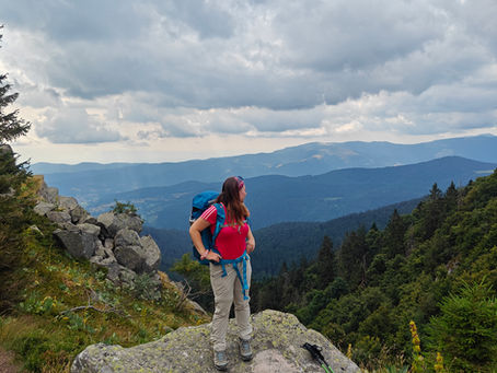 een meisje dat aan het backpacken is in de Vogezen met bergen als uitzicht