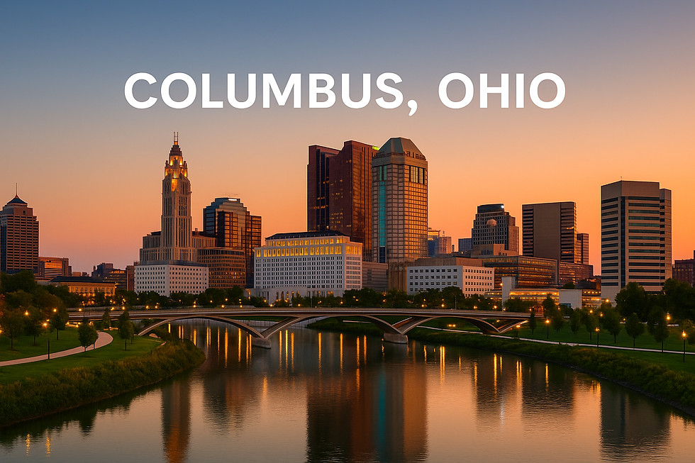 City skyline of Columbus, Ohio at sunset. Buildings reflected in a calm river, with a bridge and trees in the foreground.
