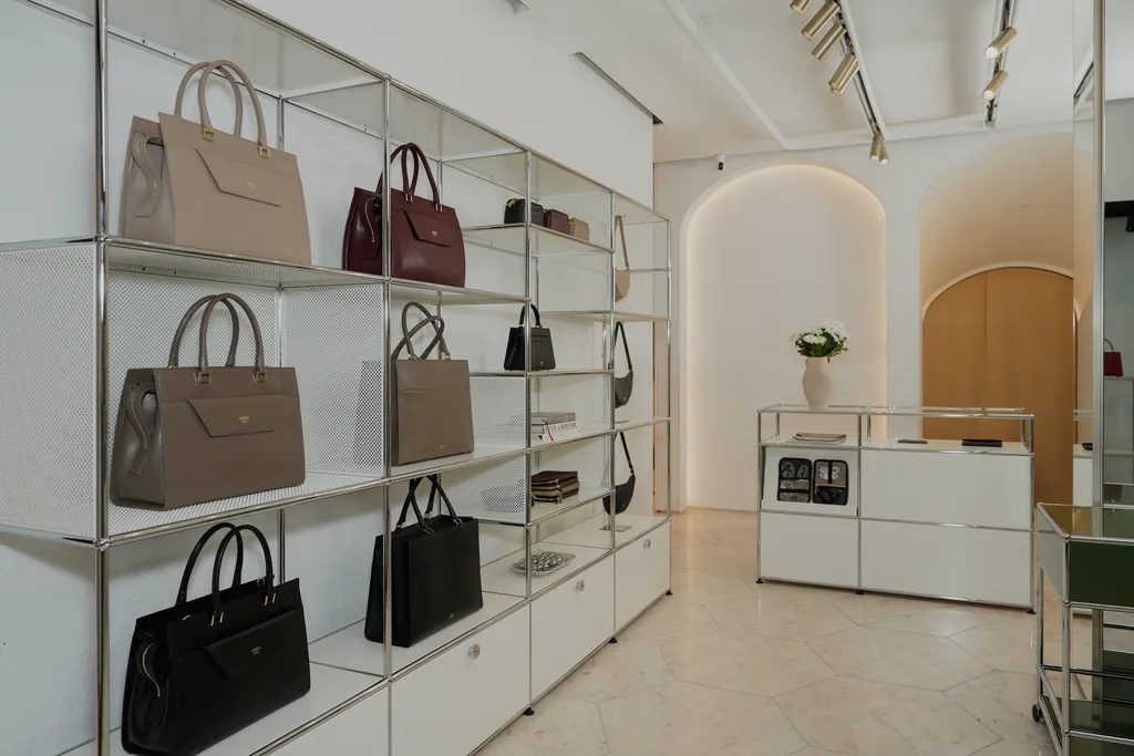 Modern and minimal interior of the AMELI Zurich store featuring handbags neatly arranged on metal shelves.