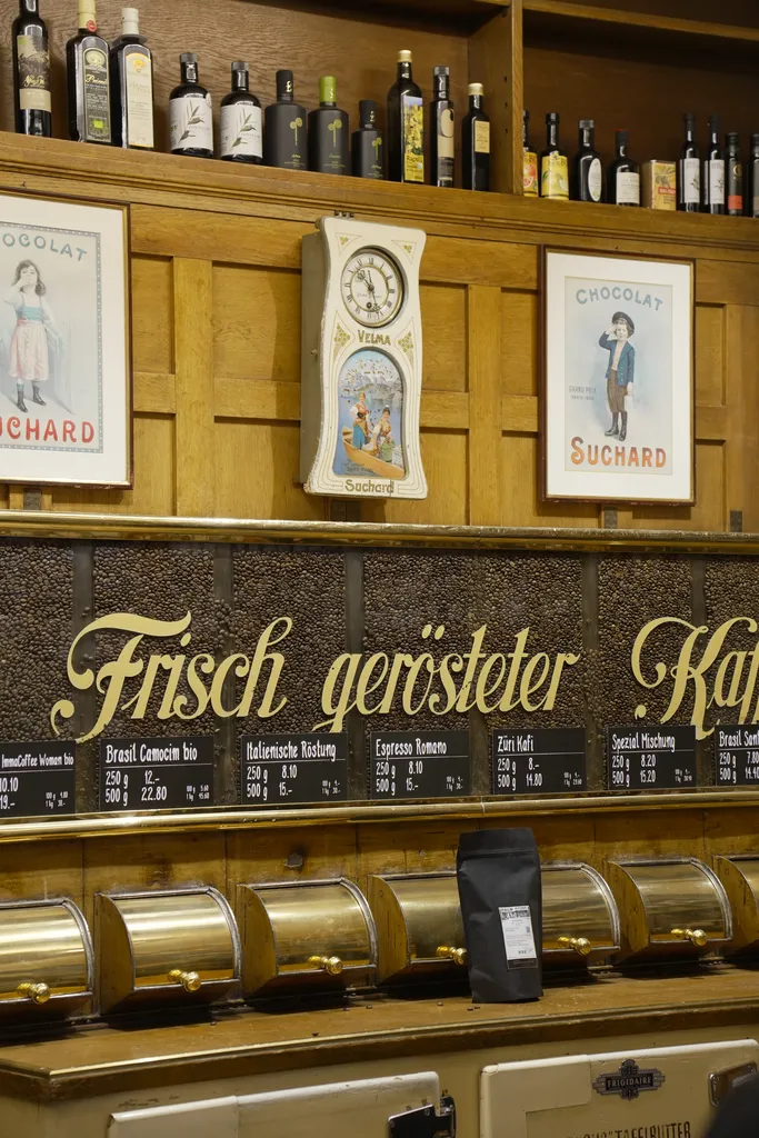 Vintage coffee dispensers with hand-labeled signs at Schwarzenbach Zurich, showcasing freshly roasted coffee varieties in a historic wooden interior.