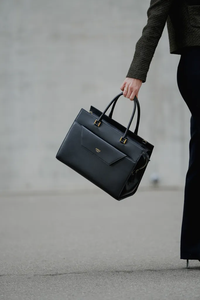 Close-up of a woman holding the black AMELI Central bag while walking, highlighting the sleek design.