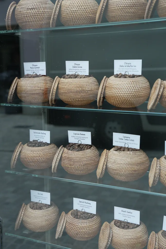 Window display at Schwarzenbach Zurich featuring traditional woven baskets filled with different coffee beans, each labeled by origin and roast style.