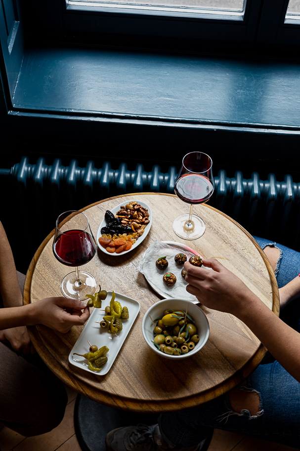 Table at COR Zurich with red wine, olives, pickles, nuts, and small bites, capturing a cozy aperitivo moment