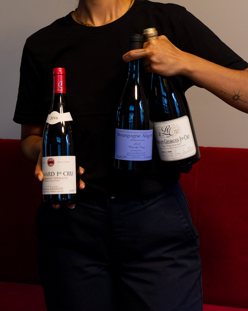Person holding three fine wine bottles at COR Zurich, showcasing the restaurant’s curated wine selection
